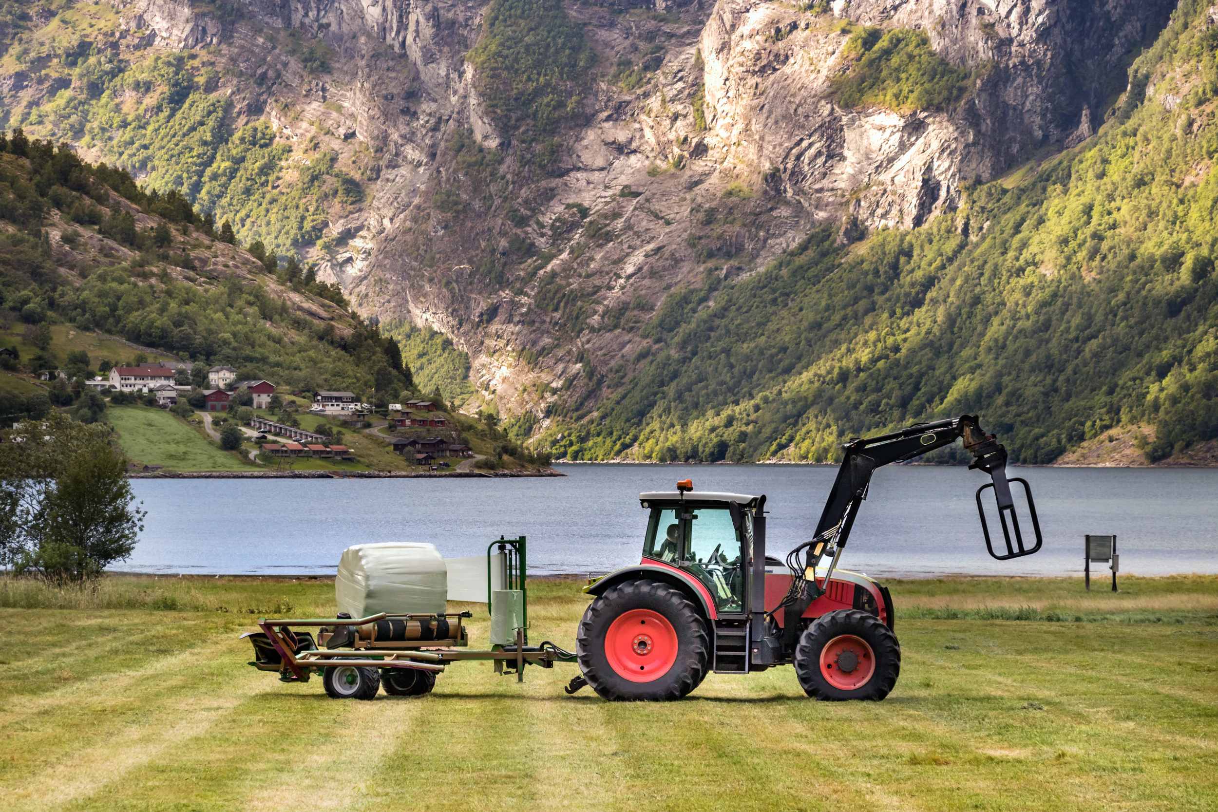 Fotografiet viser en traktor ved fjorden.